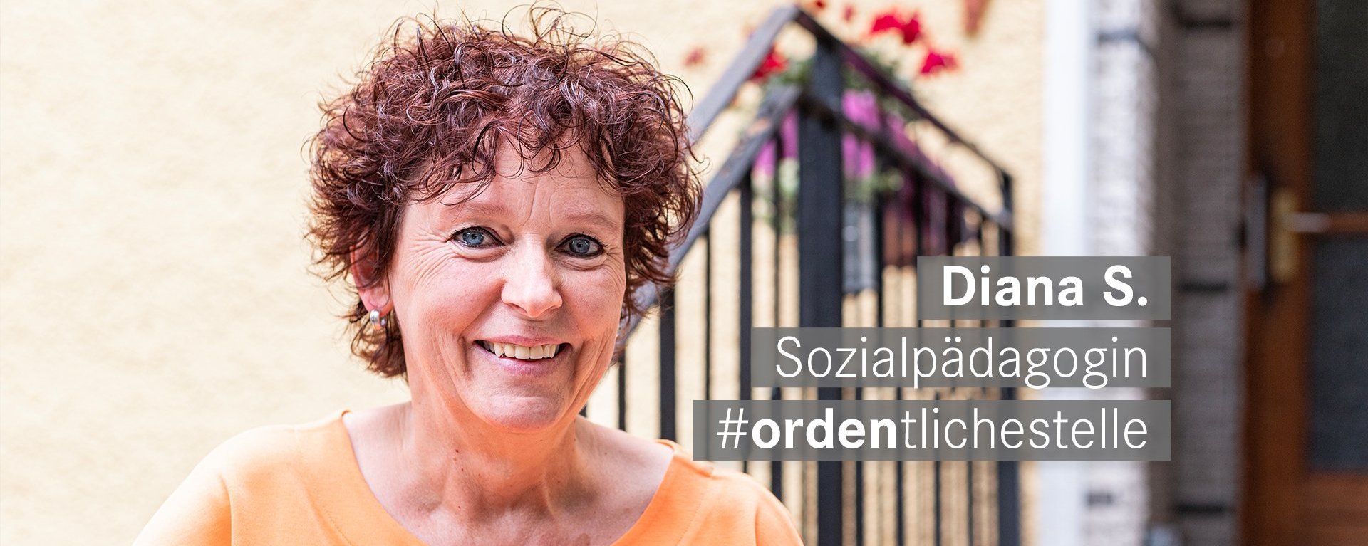 Sozialpaedagogin mit roten kurzen Locken und blauen Augen laechelt freundlich in die Kamera