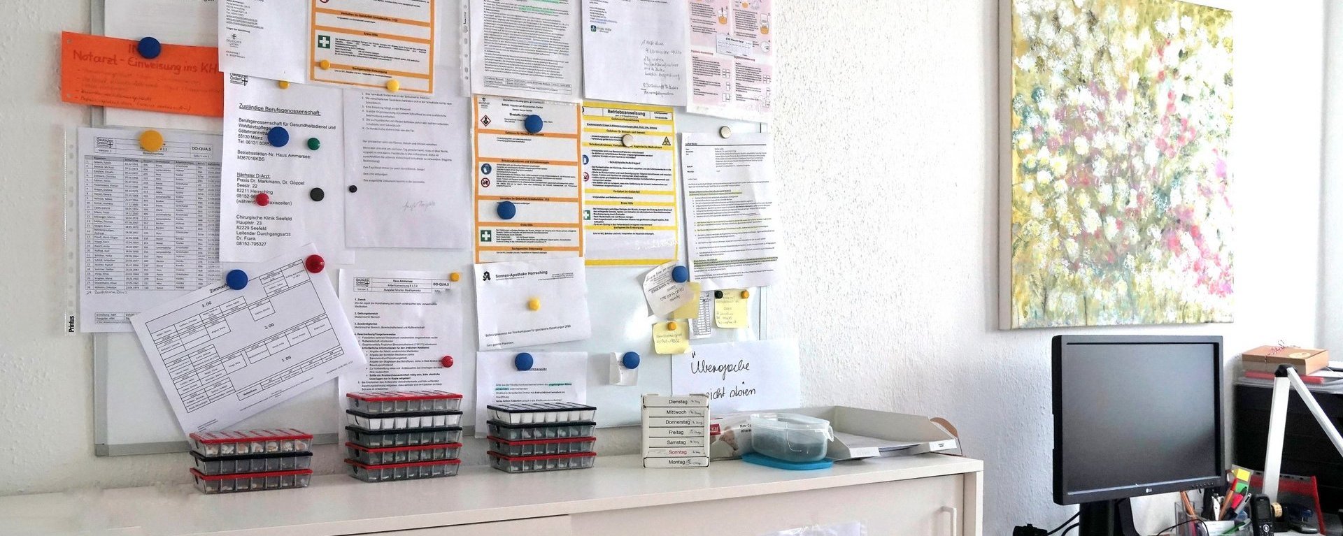 Büro: ein Computer, ein Whiteboard mit vielen Papier-Blättern