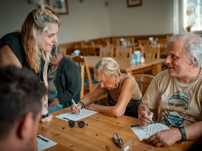 Eine freundliche Mitarbeiterin mit Brille und dunklen Haaren ist im Gespräch mit einem jungen Mann