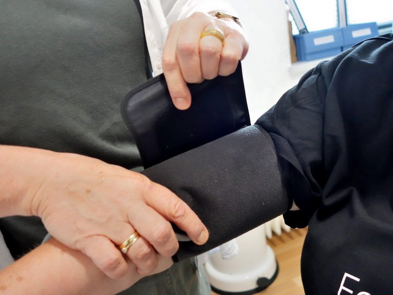 Nahaufnahme: eine Bludruck-Manschette wird am Arm befestigt