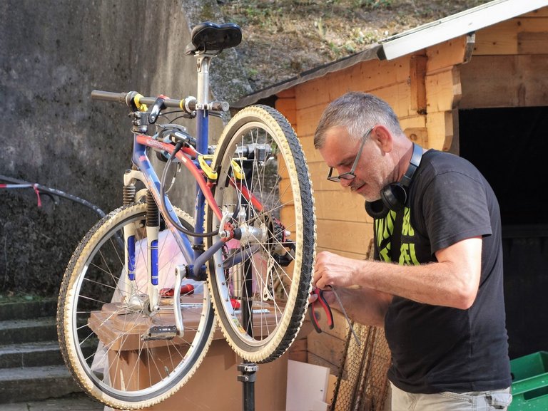 Ein Mann repariert ein Fahrrad, das in einen Fahrradständer eingespannt ist