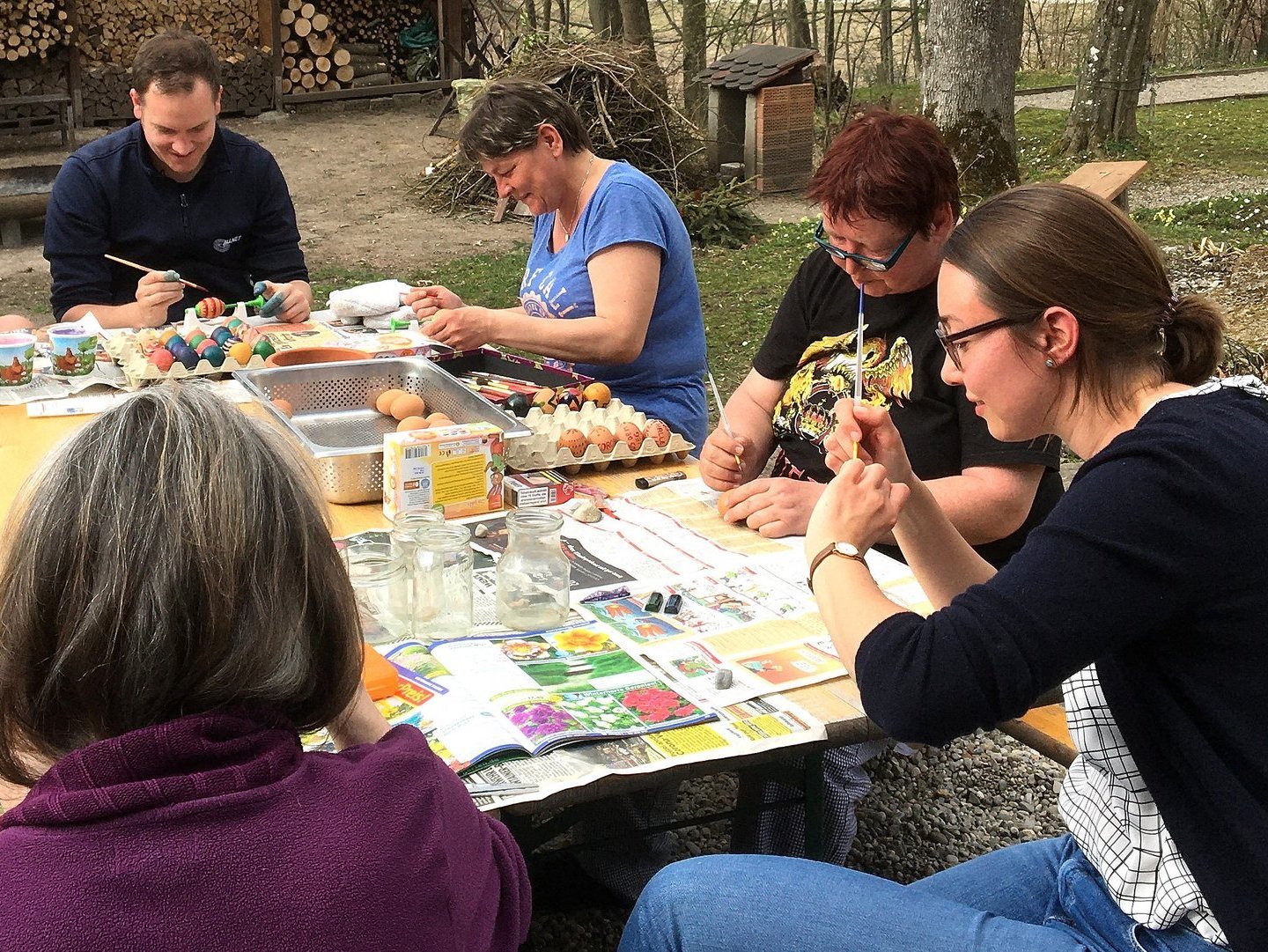 Ostervorbereitung: vier Frauen und zwei Männer im Garten beim Eier-bemalen